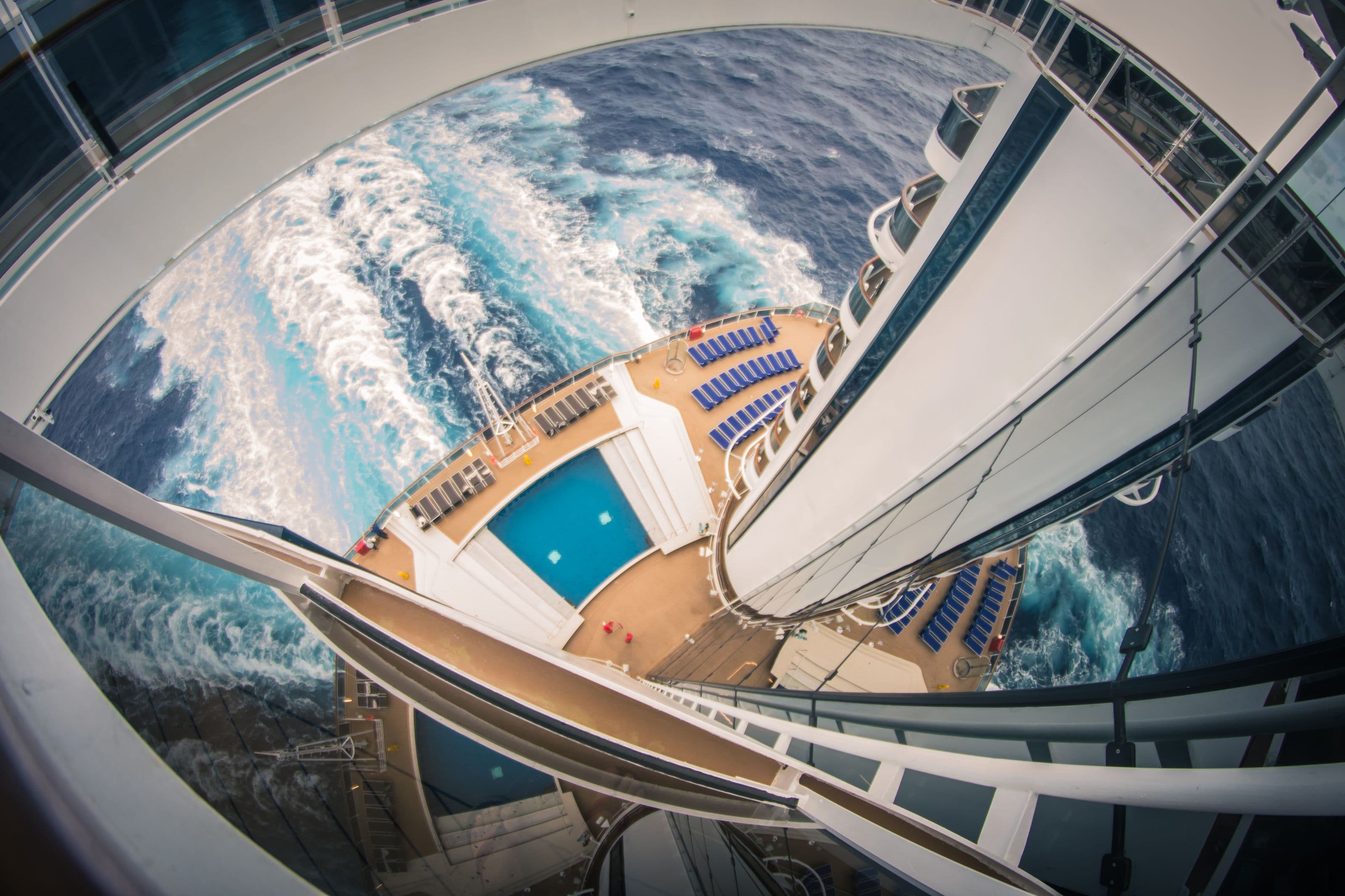 Vista desde una cubierta alta de un crucero: la piscina y una amplia estela blanca en el mar